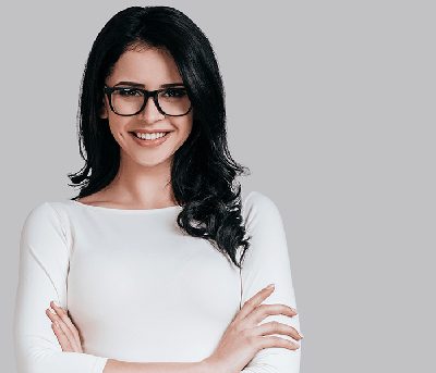 Young brunette woman with glasses standing relaxed with arms crossed; for info on overcoming dental anxiety.