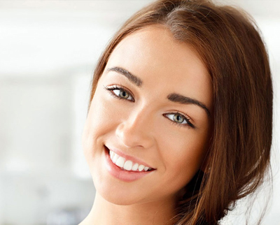 Young brunette girl smiling; for information on a perfect smile with dental implants.