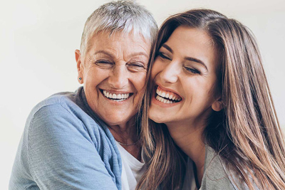 Photo of a grandmother and grandaughter smiling and hugging; for information on pinhole gum recession treatment.