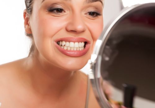 Woman looking at her teeth in a mirror portraying holistic dentistry for fillings